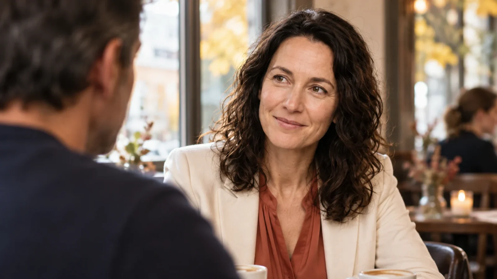 Ist sie in mich verliebt? Test, Signale und dein nächster Schritt Eine Frau blickt ihrem Gegenüber im Café mit einem vorsichtigen Lächeln zu